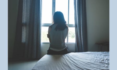 girls/women sexual exploitation prevention/intervention grants; young woman sitting on bed looking out window