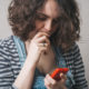 gun violence: Young woman looking at phone with concern, worry.