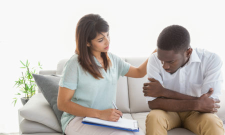 suicide: Therapist reassuring her upset patient, a young man of color, at therapy session