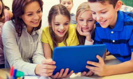 Classroom technology educator support grants; teacher and students excitedly learning from tablet device