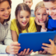 Classroom technology educator support grants; teacher and students excitedly learning from tablet device