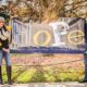 Man and woman outside hold up banner that say hope hispanic organization promoting education