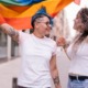 LGBTQIA+ community; Lesbian couple with playful attitude showing proudly a pride lgbt flag.