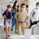 community learning centers: Group of children with face masks approach tables and chairs