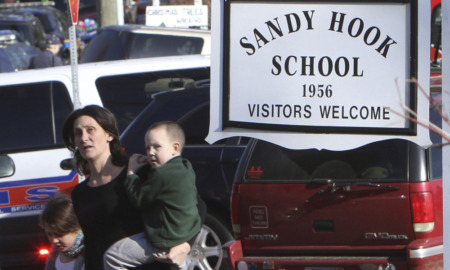Sandy Hook: Woman childing toddler stand s amidst cars next to sign saying " Sandy Hook Elementary School"
