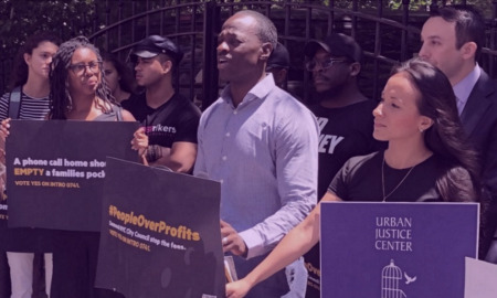 Prison phone calls: Group of adults stand holding signs in outdoor protest event holding signs about unfair phone call charges