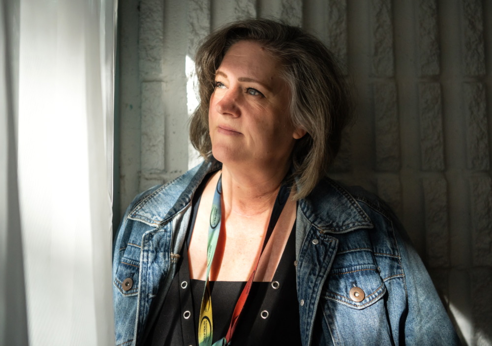 New Mexico sex trafficking: Middle-aged woam with long blonde hair wearing blue denim jacket and black blouse stares pensively to left of camera.