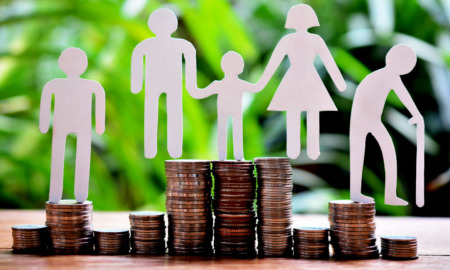 Child welfare and poverty: Paper cut out figures of people stand on top of several stacks of coins