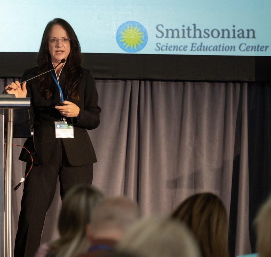 Climate change education - a woman in a black suit at a podium