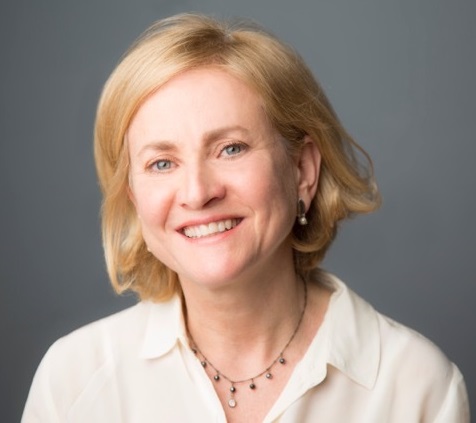 Sarah Burd Sharps headshot: white woman with mid-length hair and necklace on grey background