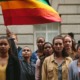LGBTQ+ community youth: group of stoic youth standing with one holding a rainbow flag