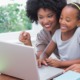 girls' and women's education and empowerment: Black mother and child smiling while on laptop together