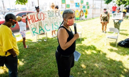 social justice grants: woman with facemask and microphone speaking in front of protest sign