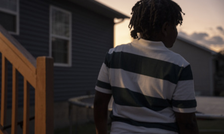Tennessee school threat law; 11-year old juvenile arrest for making threat in Tennessee: view of young black child from behind in horizontal striped shirt at dusk