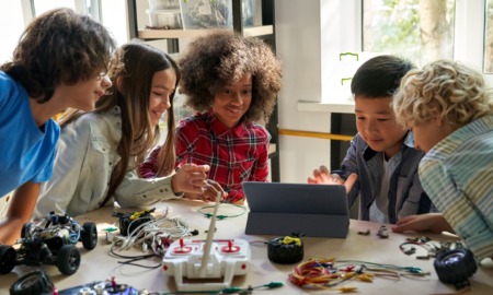 Every Hour Counts: Mixed ethnic group of preteens working togeher at table on robotics project