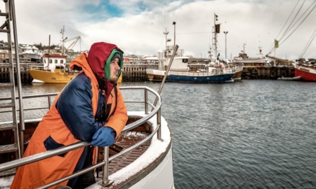 Young fishermen career development program grants: fishermen in orange jacket looking out off side of boat