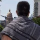 Texas international college students and deportation: Back view close up of person with plaid shawl over shoulders with TexasCapitol building in the background